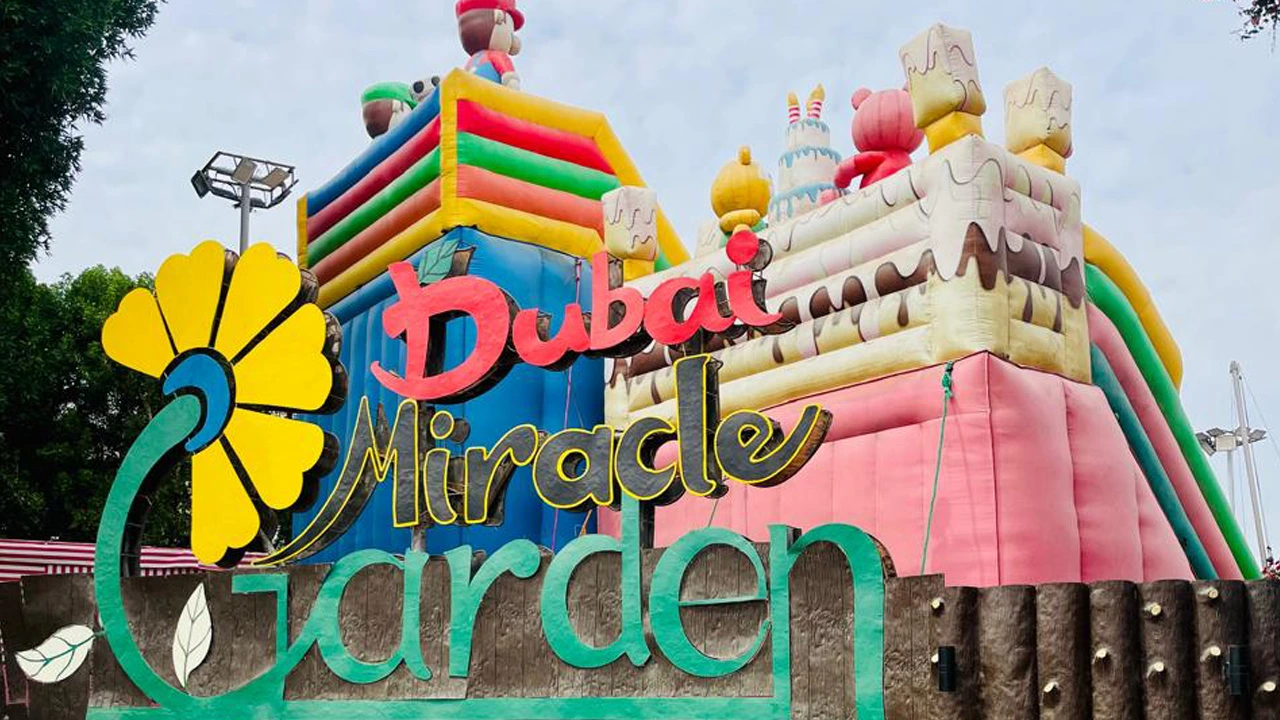 Dubai Miracle Garden entrance sign with colorful decorations and inflatable play structures in the background.
